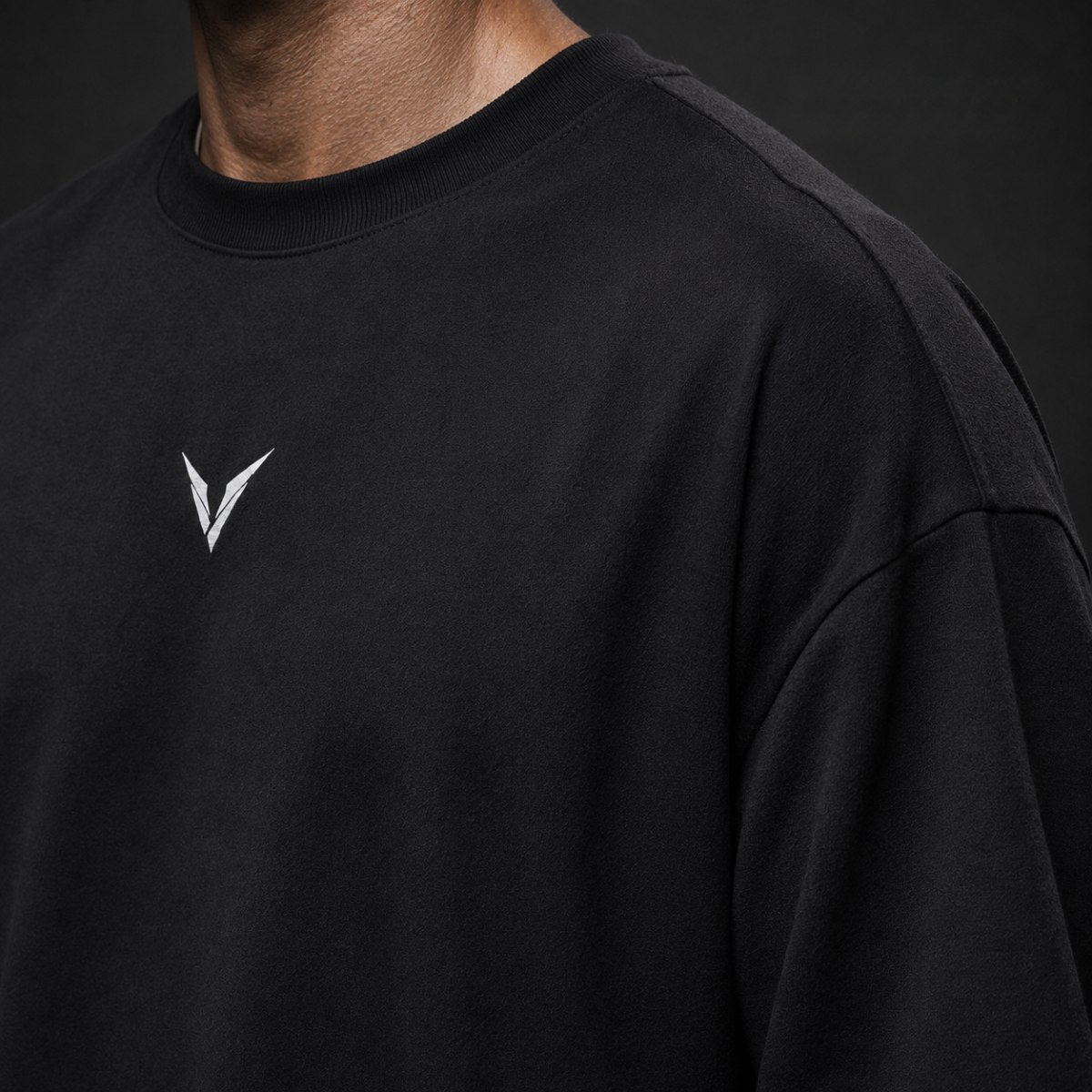 Detalhe da gola, do tecido encorpado e do símbolo frontal da camiseta VALKR